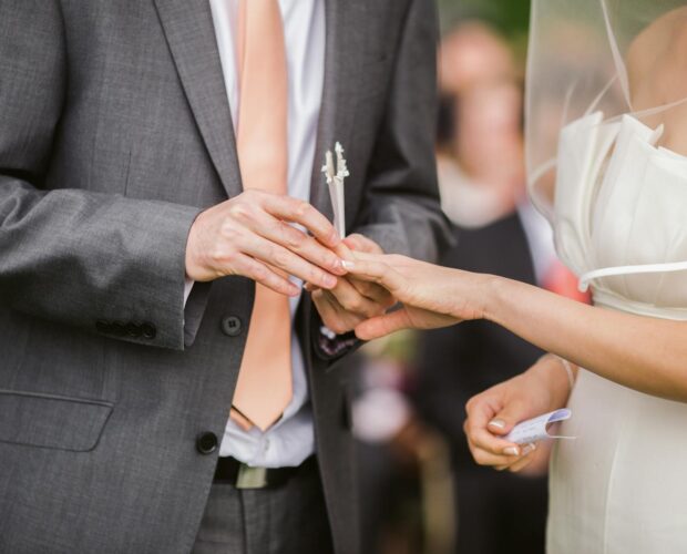 Close-up of a bride and groom exchanging rings during their wedding ceremony.